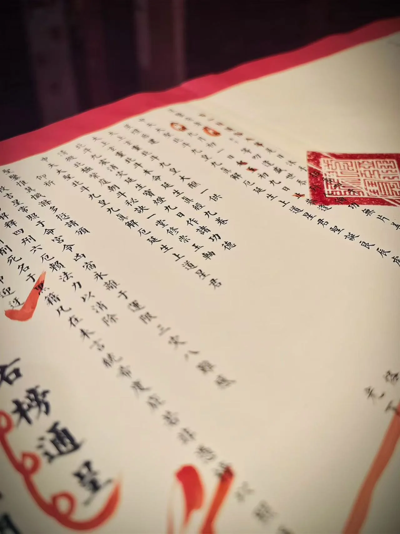 A close view of Chinese ritual text and a vermilion seal on cream paper