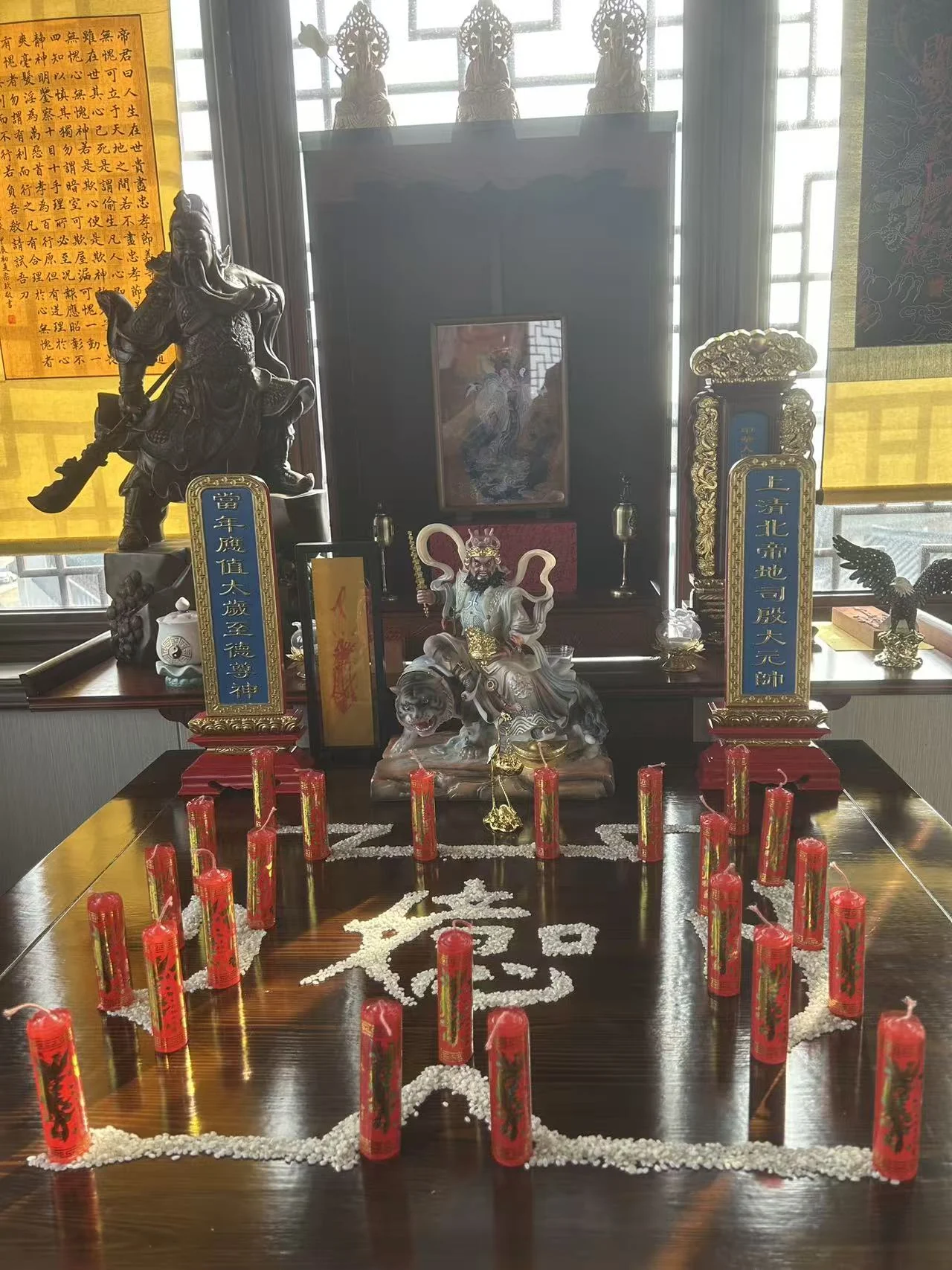 An altar with red candles, arranged grains, small figures and offerings