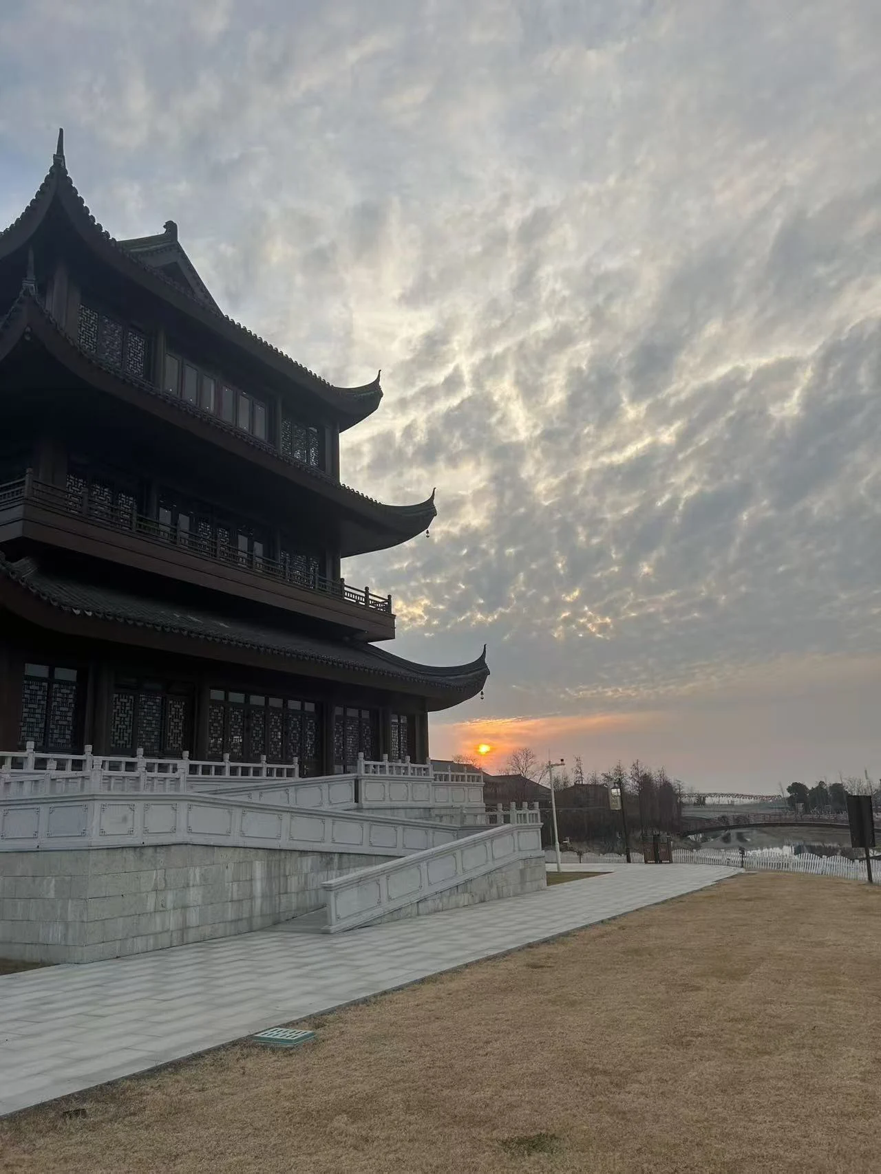 A traditional temple building beside an open courtyard at sunset