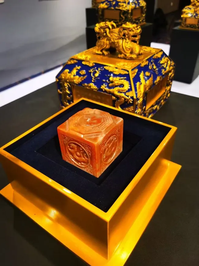A square seal with circular motifs beside its decorative case.