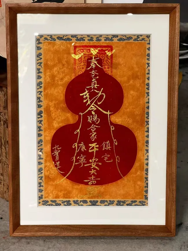 A framed red gourd silhouette filled with talismanic writing.