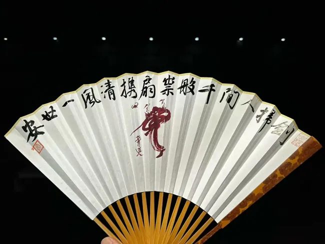 The calligraphic face of a white folding fan.