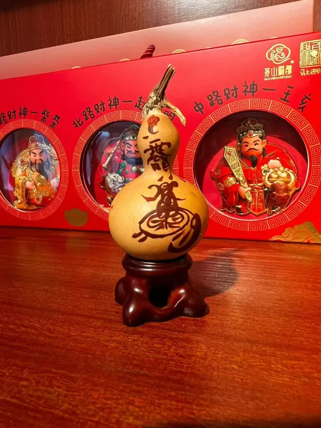 A light-coloured gourd with a large inscription, displayed on a stand.