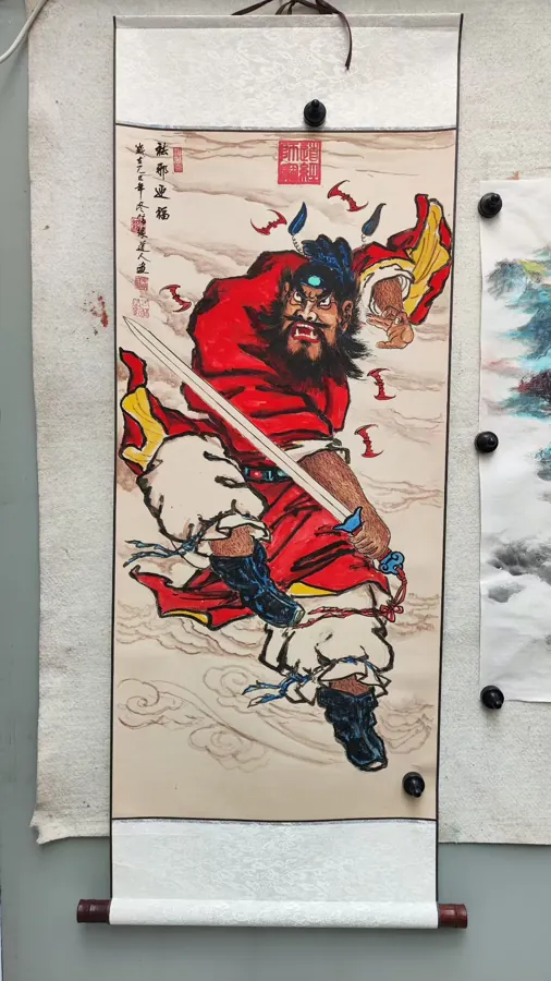 A hanging scroll with a bearded guardian figure in red robes holding a sword.