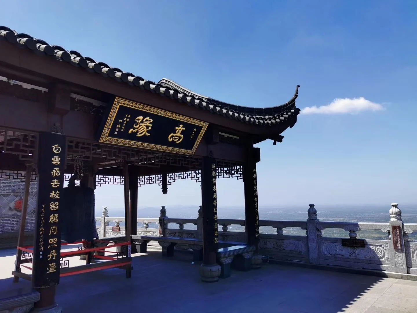 Inscribed pavilion eaves above a stone terrace with a distant landscape